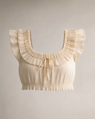 A cream-colored pleated crop top with ruffled shoulder details and a tie at the neckline, shown against a neutral beige background.